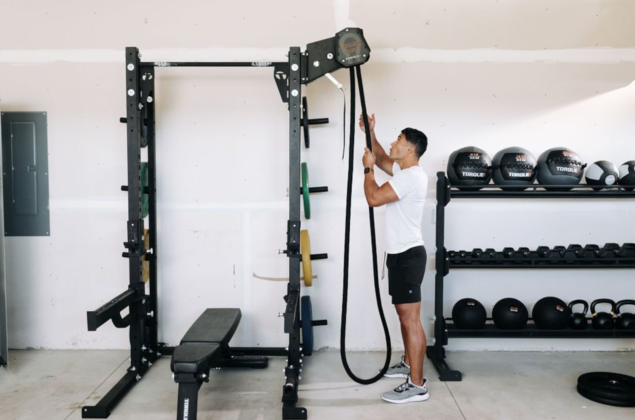 Man Pulling Endless Rope Trainer Next To Universal Storage Rack